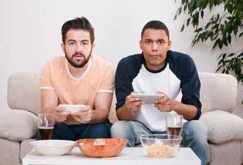 Image of happy friends playing computer games. Handsome men looking at TV screen and ready for battle with each other.