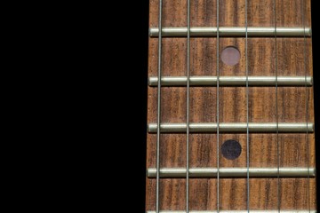 Close-up the Guitar neck aligned, Rosewood fingerboard neck on black background.
 / Color detail with the fret board of a guitar.


