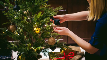 Female hands decorating a Christmas tree. girl decorates a festive Christmas tree, balls and toys Ornamental, at home in the cozy atmosphere of holiday