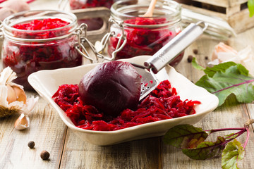 Grated beetroot marinated in jars. Wooden background.