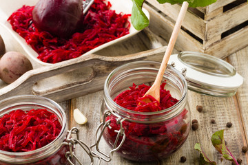 Grated beetroot marinated in jars. Wooden background.