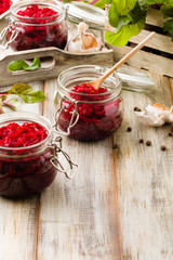 Grated beetroot marinated in jars. Wooden background.