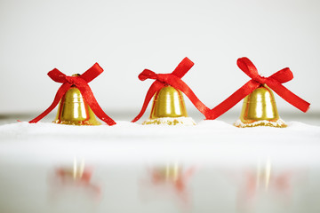 Decorative golden bells for Christmas and New Year, on white snow, with copy space