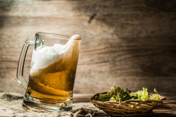 Beer spills from tankard on empty wooden background