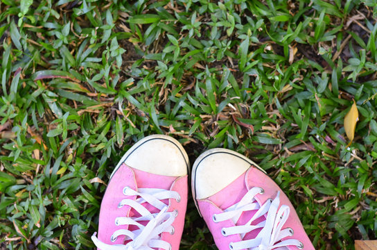 Pink sneakers on a green grass. Rest in the park without shoes.
