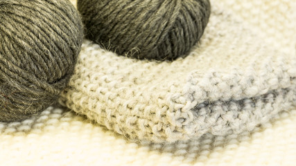 Strickstück mit Wolle im Knaeul in Grau und Anthrazit auf getricktem Untergrund