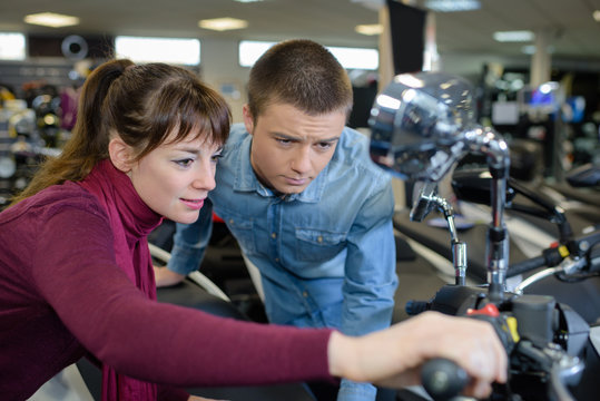 young smiling couple checking motorcycle at motorbike store