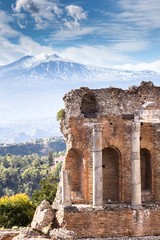Ruins and columns of antique greek theater in Taormina and Etna Mount in the background. Sicily,...