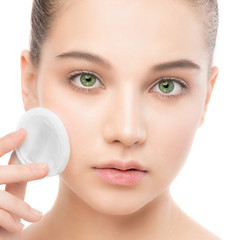 Young girl cares for face skin relaxation. Beautiful young brunette woman with clean perfect fresh skin using cotton pad. Youth and skin care concept. Isolated on a white.