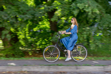 Beautiful young woman and vintage bicycle, summer. Red hair girl riding the old black retro bike outside in the park. Having fun in the city