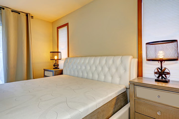 White double bed front view, with two lamps on bedside tables.
