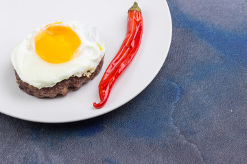 Steak with fried egg and chili pepper