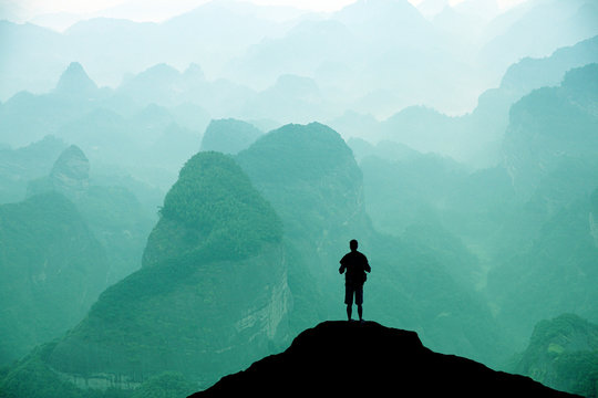 Climber standing the top of mountain in sunset background.
