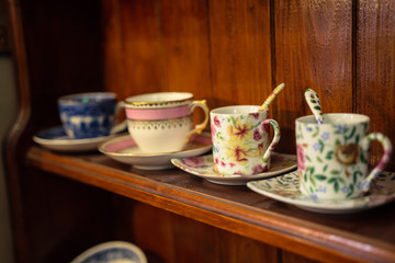 Line of four cups on the wooden shelf in a vintage shop in Bruges, Belgium