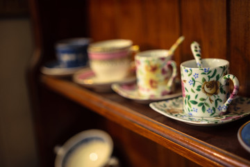 Line of four cups on the wooden shelf in a vintage shop in Bruges, Belgium
