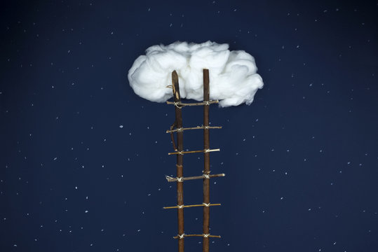 Largas escaleras de madera que llegan hasta una nube solitaria en medio del cielo estrellado de noche.