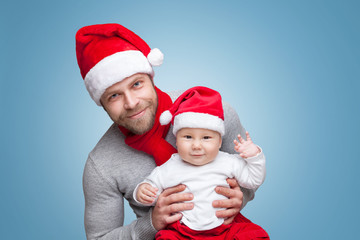 Father with baby boy wearing Santa hats celebrating Christmas