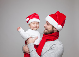 Father with baby boy wearing Santa hats celebrating Christmas
