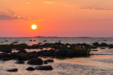 Fototapeta na wymiar Sunset rocky beach, peaceful sea, orange sky. Kihnu, small island in Estonia. Baltic sea, Europe. Natural environment background.