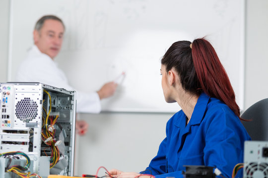 teacher showing student on whiteboard how to fix a computer - Powered by Adobe
