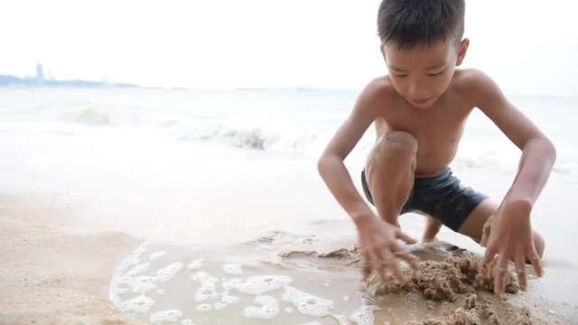 Slow motion of young Asian Thai boy playing on the sand beach