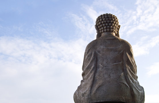 Sitting Buddha image on blue sky background.