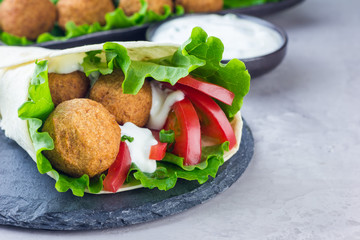 Chickpea falafel balls with vegetables and sauce, roll sandwich preparation, horizontal