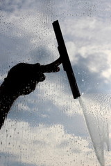 man cleaning the window with cloudy background 
