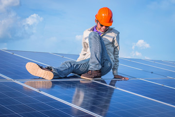 electrician working on checking and maintenance equipment at industry solar power; engineer sitting on solar panel