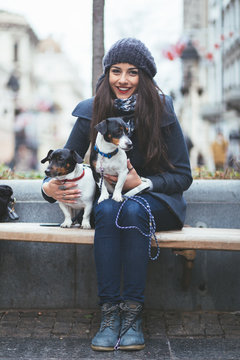 Beautiful young brunette woman enjoying city street outdoor together with her two gorgeous Jack Russell terriers. 