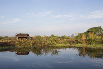 little hut in a green field near a pond with reflection