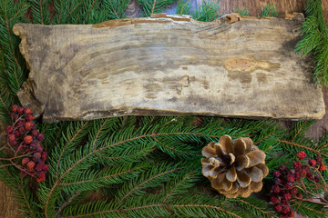 wooden board on a background of fur-tree branches and berries