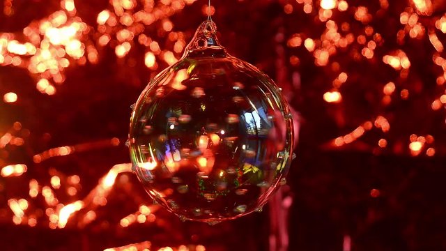 Palla di Natale in vetro ruota su se stessa, fondale rosso luccicante