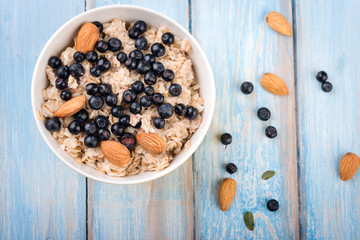  Homemade oatmeal with berries and nuts on wooden background. Healthy breakfast. Top view.