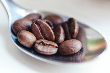 coffee beans in coffee spoon on white