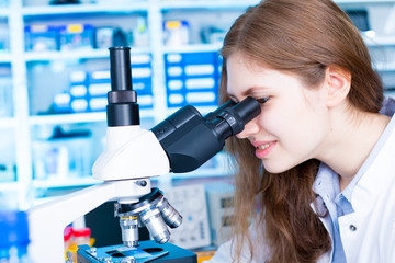 Young scientist studying new substance or virus in microscope. .Scientist using a binocular microscope in a laboratory.Close up of a scientist posing with scientific devices in a laboratory