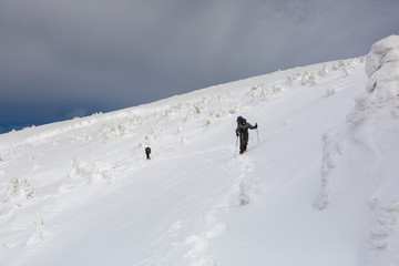 Fototapeta na wymiar Man hiking in winter mountains before thunderstorm