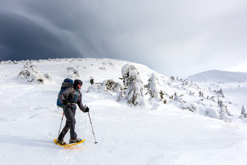 Man hiking in winter mountains before thunderstorm