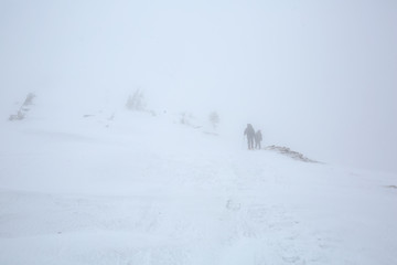 Backpacker walk in strond thunderstorm in winter mountains