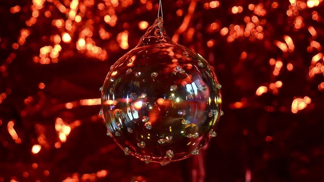 Palla di Natale in vetro ruota su se stessa, fondale rosso luccicante