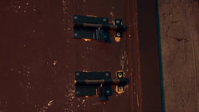 Massive metal hasps on the old scratched door