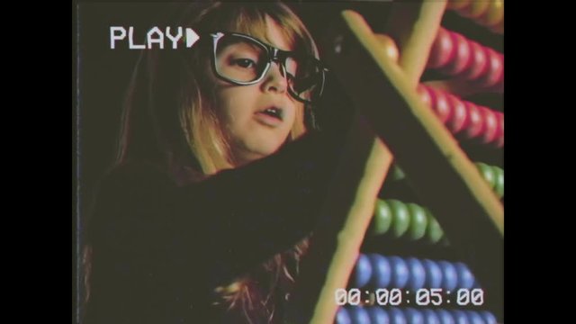 Vhs retro fake shot: a cute little girl playing with an abacus and learning to count. Detail shot of the beads on the rows.
