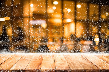 Empty wood table top with snowfall and bokeh cafe restaurant in winter