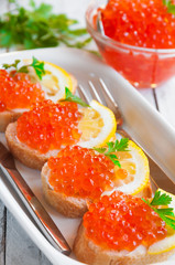 Red caviar on bread with lemon and parsley