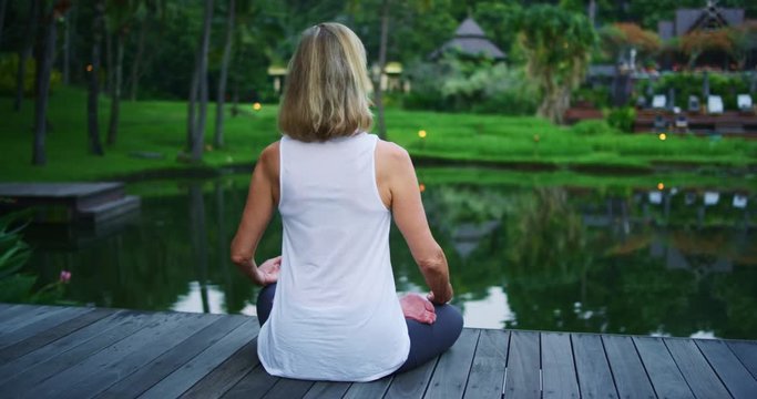 Woman practicing yoga meditating outdoors on beautiful deck, health and wellness concept