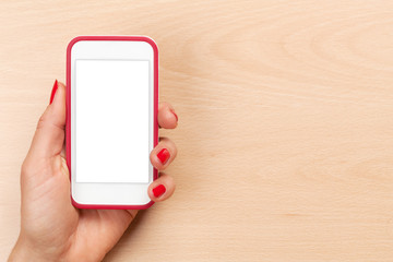 Female hand holding a smartphone above desk table