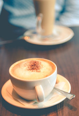 Cappuccino coffee with chocolate on top in cup on wooden table i