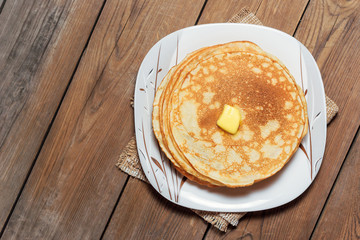 A stack of pancakes on a plate with butter