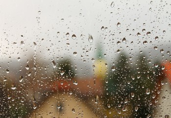 Rain drops on window with house and church in background