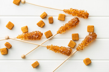 Brown amber sugar crystal on wooden stick.